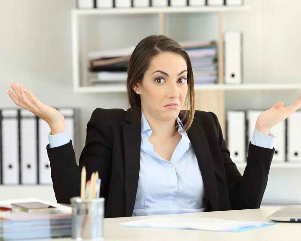 A brown-haired girl shrugging in confusion. She's wearing an open suit jacket and white shirt.