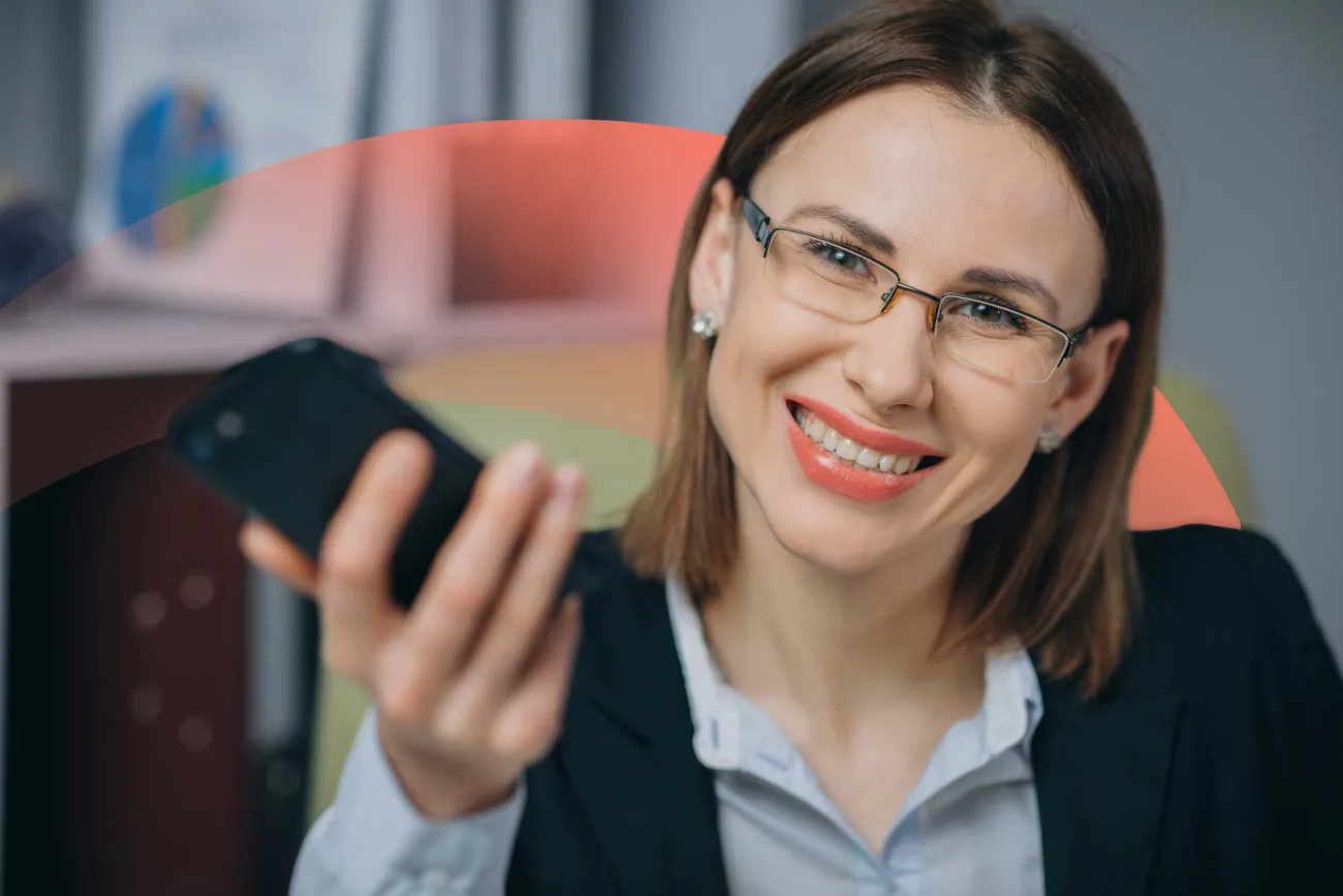 Smiling businesswoman holding a phone, and smiling at the camera.