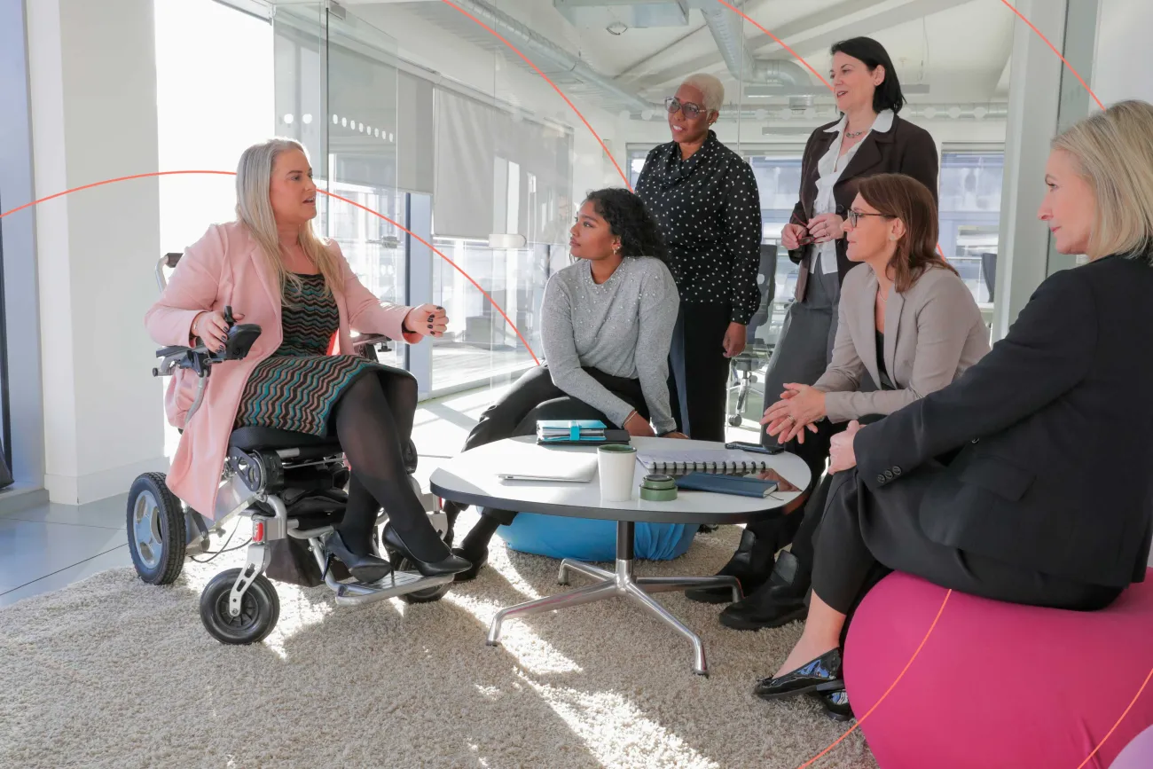Diverse group of professionals having a meeting, with one person in a wheelchair leading the discussion.