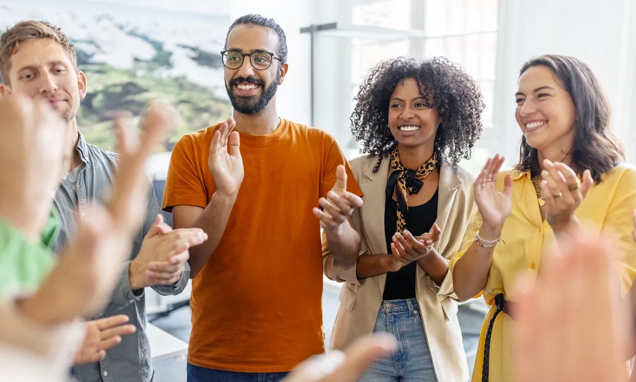 Group of diverse people smiling and applauding indoors