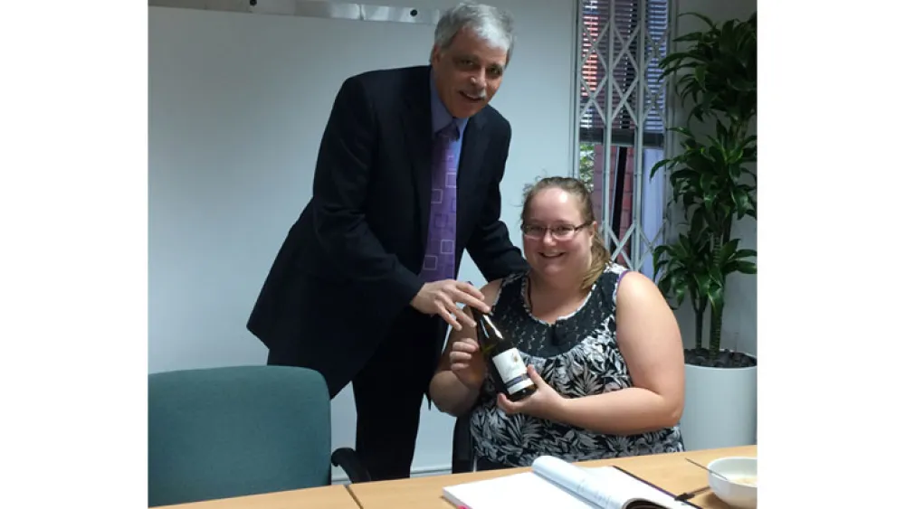 Raj handing a lady a bottle of wine who achieved a 99% pass mark for the AgilePM Foundation exam