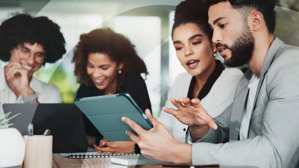 Group looking at digital devices and documents while collaborating in office setting