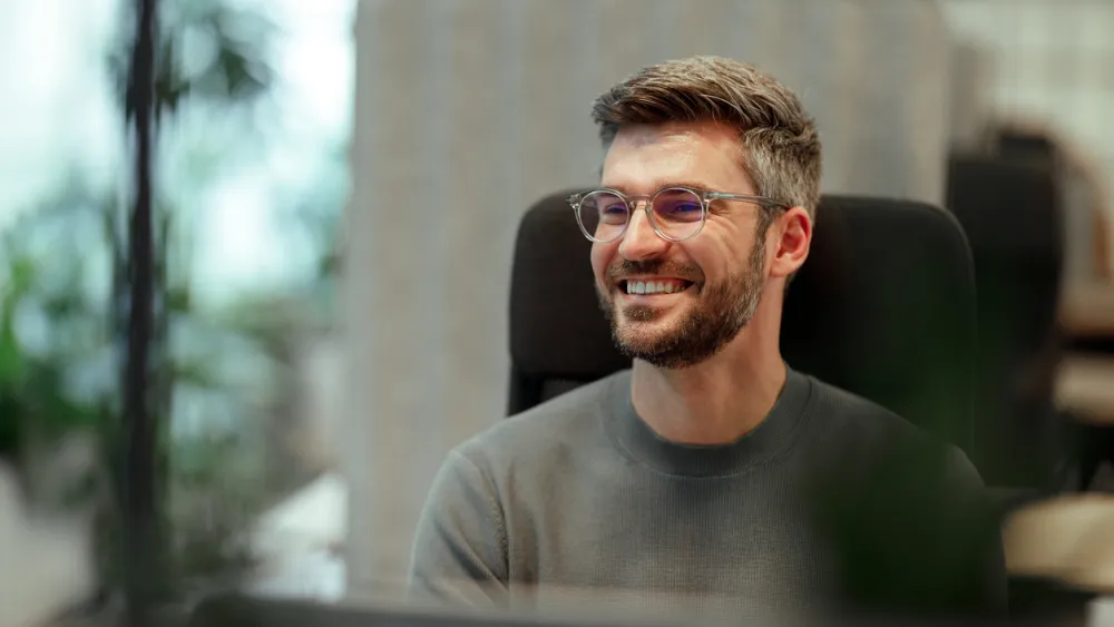 Man in office smiling at a computer
