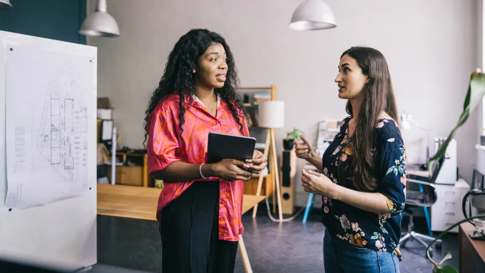 Two women standing and talking in a modern office space