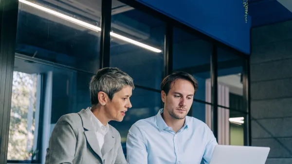 Two people working together at a laptop in a modern office