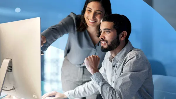Two professionals collaborating at a computer, reviewing data and working together in an office.