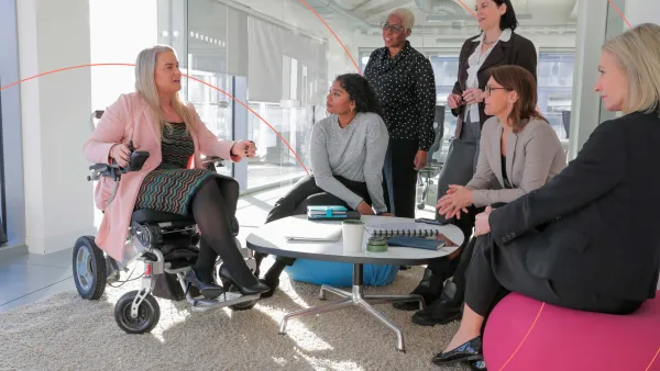 Diverse group of professionals having a meeting, with one person in a wheelchair leading the discussion.